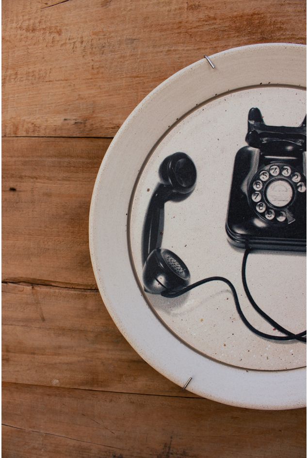 prato de concreto branco com estampa de telefone retrô preto em detalhes com fundo de madeira